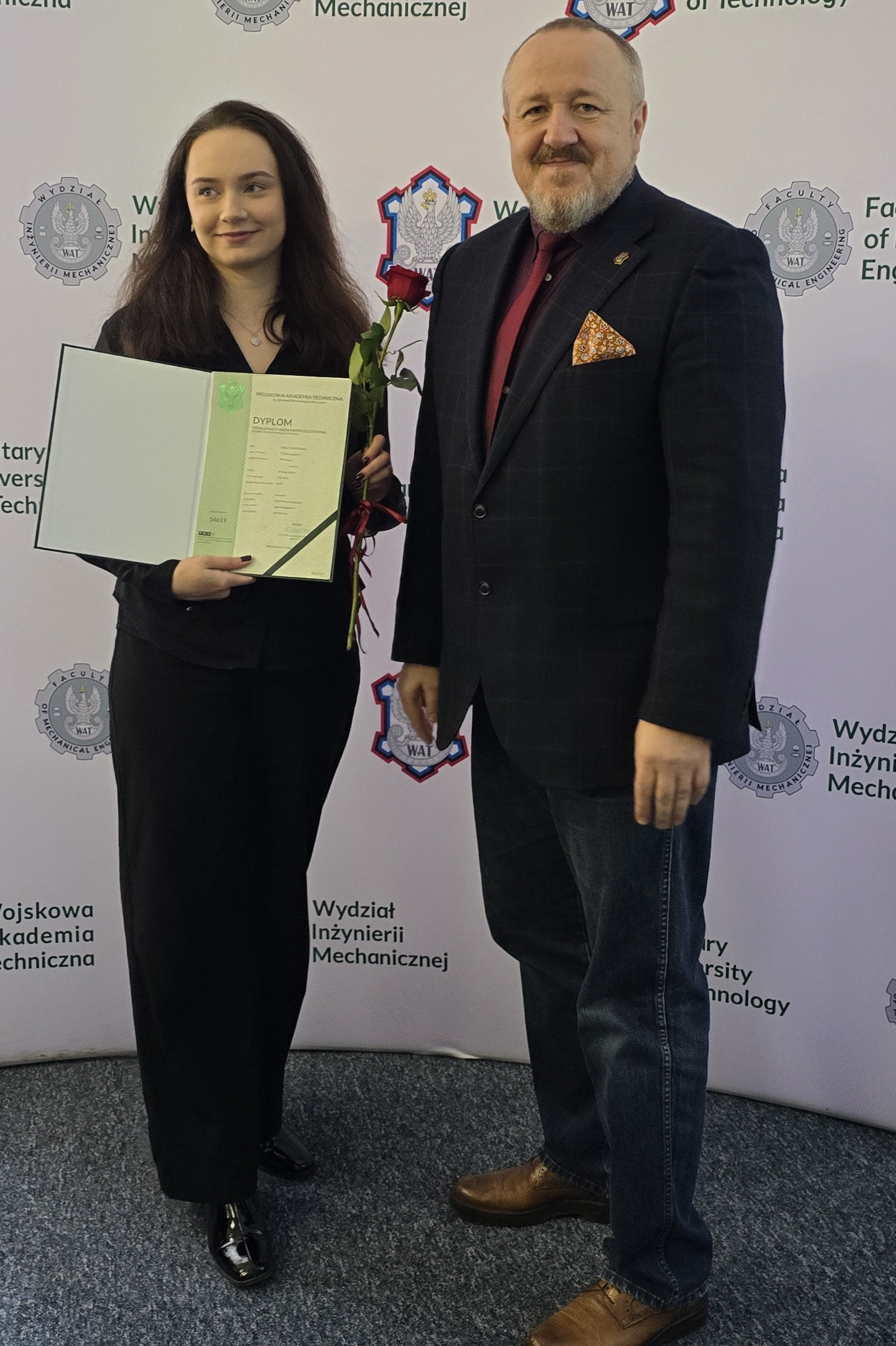 Fot. 5. Zofia Kwiecińska i dziekan Jerzy Małachowski na tle ścianki wydziałowej z logiem WIM WAT.